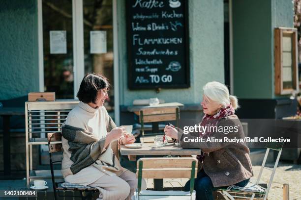 senior female friends at an outdoor cafe - senior women cafe stock pictures, royalty-free photos & images