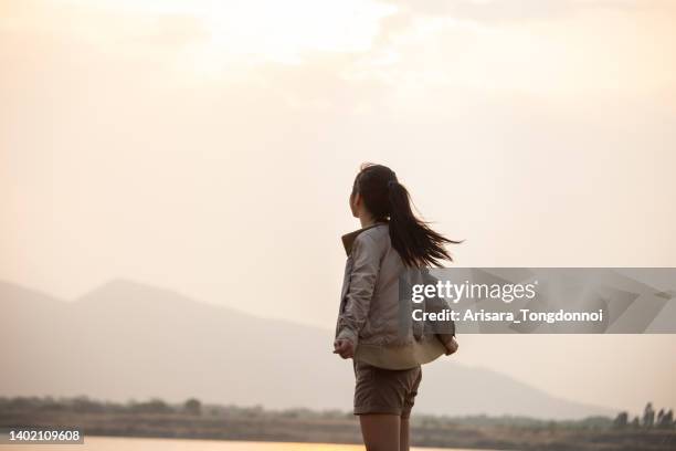 una donna che aspetta il tramonto dietro la montagna - fato foto e immagini stock