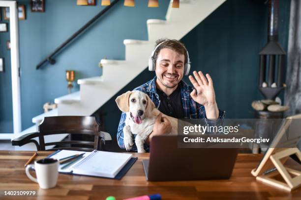 smiling male freelancer and his dog waving to client during video conference - dog waving stock pictures, royalty-free photos & images