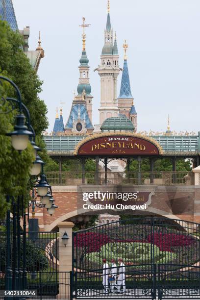 Staff members walk by the gate of Disneyland on June 10, 2022 in Shanghai, China. Shanghai Disney Resort is resuming partial operations, with reduced...