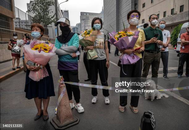 Parents and relatives hold flowers as they wait for students to emerge after finishing the final day of the National College Entrance Examination,...