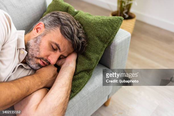 shot of a man relaxing on the sofa at home - sleep routine stock pictures, royalty-free photos & images