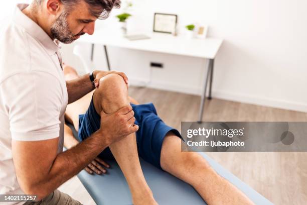gros plan des mains d’un physiothérapeute donnant un traitement thérapeutique au patient - hand on knee photos et images de collection