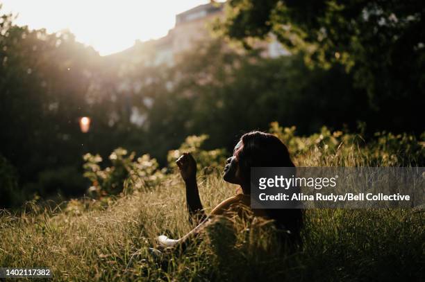 young woman daydreaming in a park - golden hour woman stock pictures, royalty-free photos & images