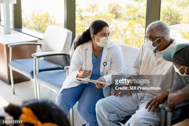 doctor talks to her patient - waiting room clinic stock pictures, royalty-free photos & images