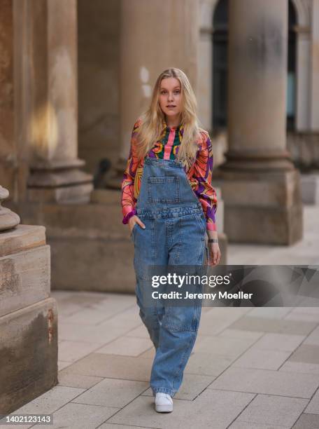 Lil Paulin seen wearing a colorful shirt blouse, a dark blue denim dungarees/jumpsuit and white sneakers on June 09, 2022 in Hamburg, Germany.