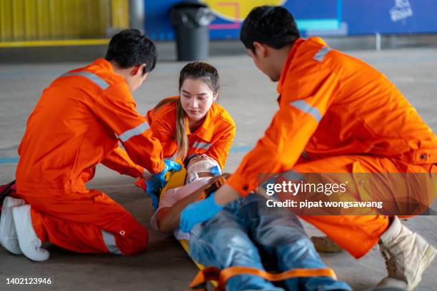 asian paramedic who is a full-time ambulance staff are providing first aid to the accident victims send to the hospital for further treatment. - injured street stockfoto's en -beelden