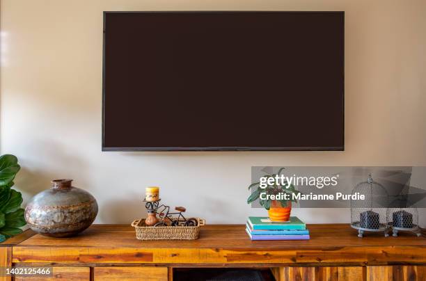 a wall mounted tv above a sideboard - decorative urn stock-fotos und bilder