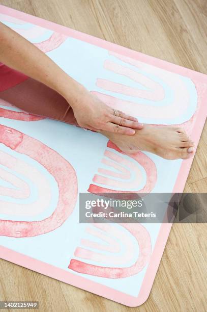 woman touching her toes on a yoga mat - teen stockfoto's en -beelden