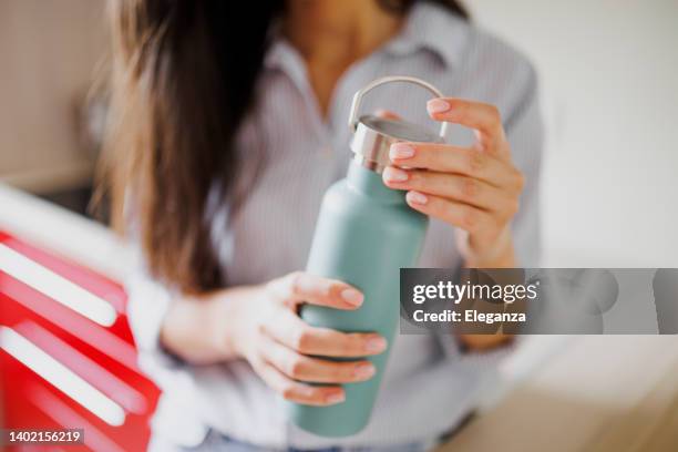 close up of woman drinking water from reusable water bottle in kitchen - reusable stock pictures, royalty-free photos & images
