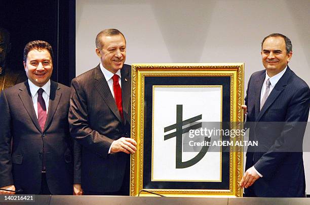 Turkish Prime Minister Recep Tayyip Erdogan , flanked by his deputy Ali Babacan and Central Bank Governor Erdem Basci, presents the new symbol for...