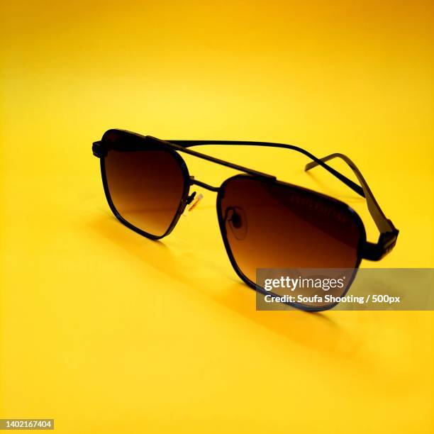 close-up of sunglasses against yellow background - tinted sunglasses stock pictures, royalty-free photos & images