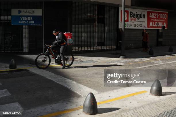 Food delivery worker on a bicycle waits for the green light next to closed storefronts with for sale and rent signs downtown on June 10, 2022 in...