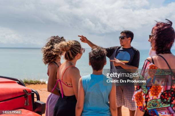 tourists listening to tour guide on the beach - royal tour stock pictures, royalty-free photos & images