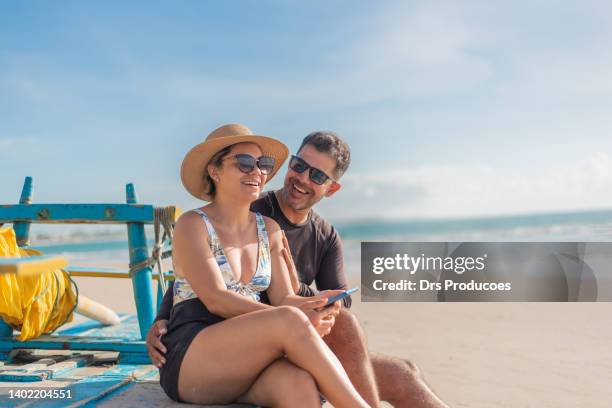 tourist couple using smartphone on the beach - 40s couple stockfoto's en -beelden