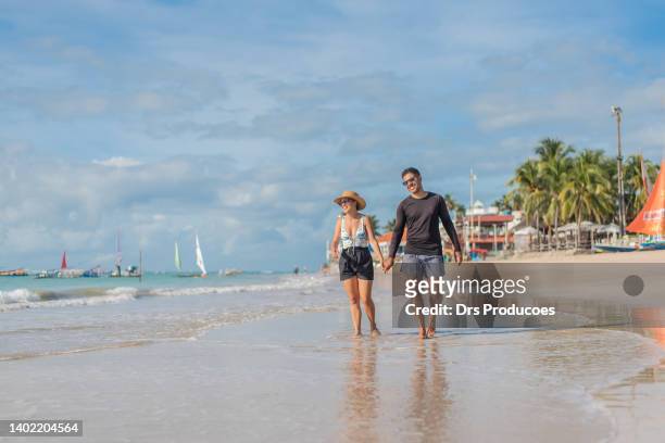 pareja de turistas caminando por la playa - porto galinhas fotografías e imágenes de stock
