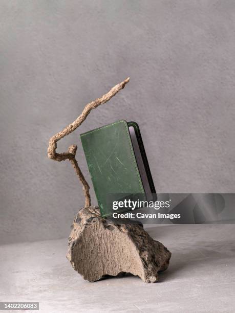 green leather document cover on grey stone as podium - podium mode stock-fotos und bilder