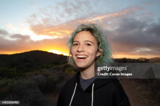 teen girl laughing while on a hiking trail with a sunset behind her - green hair stock pictures, royalty-free photos & images