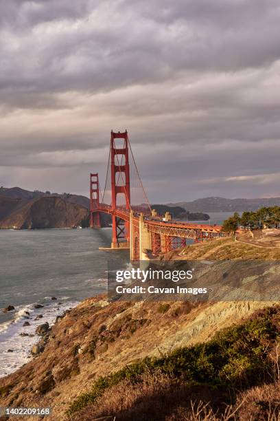 wide angle view of golden gate bridge against stormy sky at sunset - the presidio stock pictures, royalty-free photos & images