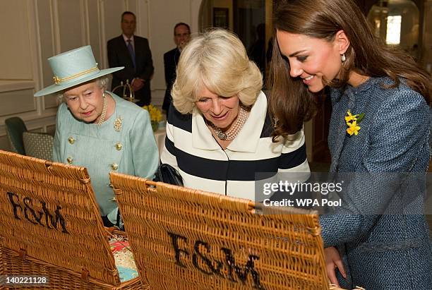 Queen Elizabeth II, Camilla, Duchess Of Cornwall and Catherine, Duchess of Cambridge look inside their hampers filled with gifts while visiting...