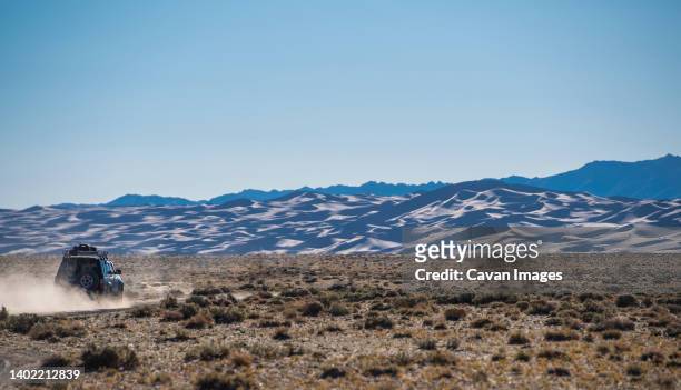 suv driving past the great sand dunes of the gobi desert - mongólia interior - fotografias e filmes do acervo