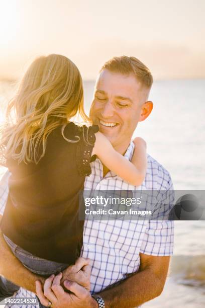 forty year old father holds five year old daughter laughing on beach - 2 year old blonde girl father ストックフォトと画像