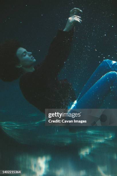 woman in jeans sinking underwater in swimming pool - wet jeans stock-fotos und bilder