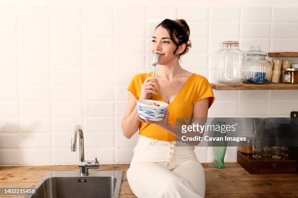 portrait of beautiful young woman having breakfast in the kitchen. - kitchen conceptual stockfoto's en -beelden