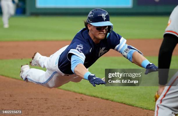 Bobby Witt Jr. #7 of the Kansas City Royals dives into third past Tyler Nevin of the Baltimore Orioles for a triple in the third inning at Kauffman...