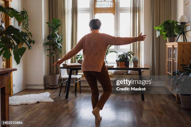 rear view of senior woman dancing in living room at home - 60 64 anos imagens e fotografias de stock