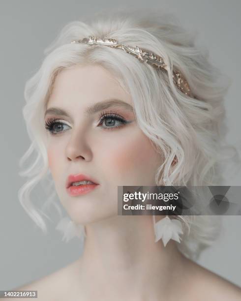 junges blondes model im studio. frau mit schöner luxuriöser griechischer frisur im weißen kleid. mädchen mit schmetterling zur hand. goldener kranz. albino. schönheitsporträt. griechische göttin. reinheit und unschuld - petite young models stock-fotos und bilder