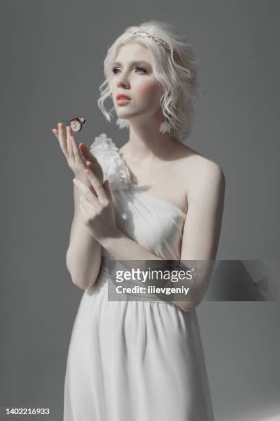 young blonde model in studio. woman with beautiful luxurious greek hairstyle in white dress. girl with butterfly on hand. golden wreath. albino. beauty portrait. greek goddess. purity and innocence - europe bride stock pictures, royalty-free photos & images