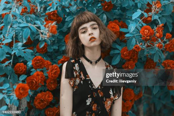 redhead model on background of roses bush. fabulous asian girl with red lips in dress on awesome summer background. rose garden. woman portrait. blue toning. cyan color. spring flowers. bob hairstyle - short necklace stock pictures, royalty-free photos & images