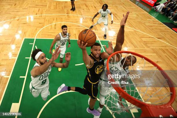 Stephen Curry of the Golden State Warriors drives to the basket against Derrick White and Al Horford of the Boston Celtics in the first half during...