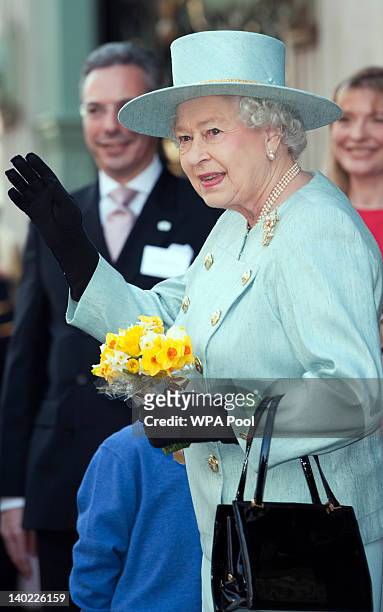 Queen Elizabeth II, carrying posy of daffodils given to her by a wellwisher on St David's Day, waves as she departs Fortnum & Mason store on March 1,...