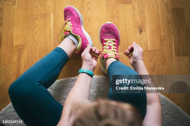 young sporty woman with smart watch tying shoelaces - women running fotografías e imágenes de stock