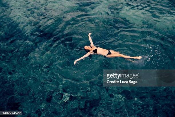 female enjoying a relaxing sea swim in ibiza - floating on water stock-fotos und bilder