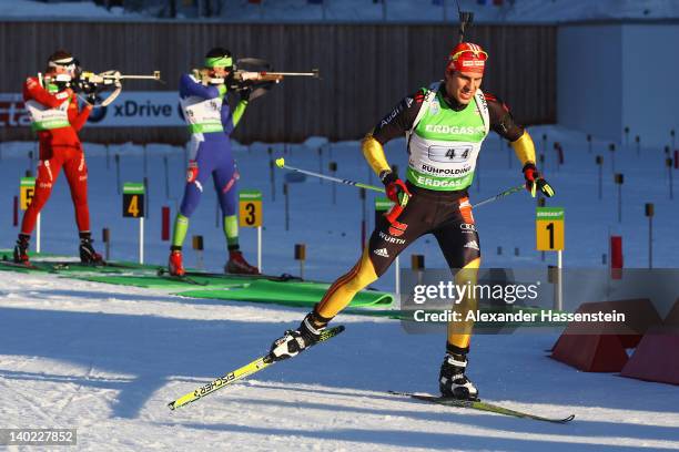 Arnd Peiffer of Germany leaves the shooting range whilst Jakov Fak of Slovenia and Emil Hegle Svendsen of Norway comeptes during the IBU Biathlon...