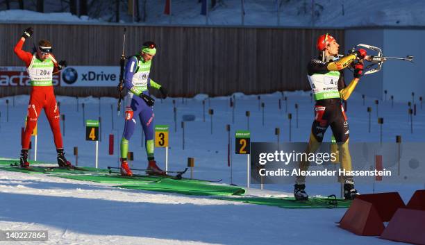 Arnd Peiffer of Germany comeptes at the shooting range with Jakov Fak of Slovenia and Emil Hegle Svendsen of Norway comeptes during the IBU Biathlon...