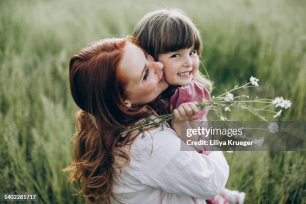 close-up portrair of mother and little daughter on a walk in the field. - spring ahead stock-fotos und bilder