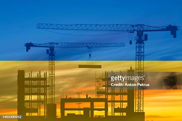 construction cranes on the background of the flag of ukraine. rebuilding cities after the war - rebuilding fotografías e imágenes de stock