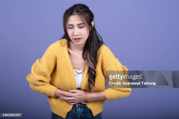 young girl holding her stomach and frowns. teenage girl has a stomach ache. female writhes in pain. - diarrhoea stockfoto's en -beelden