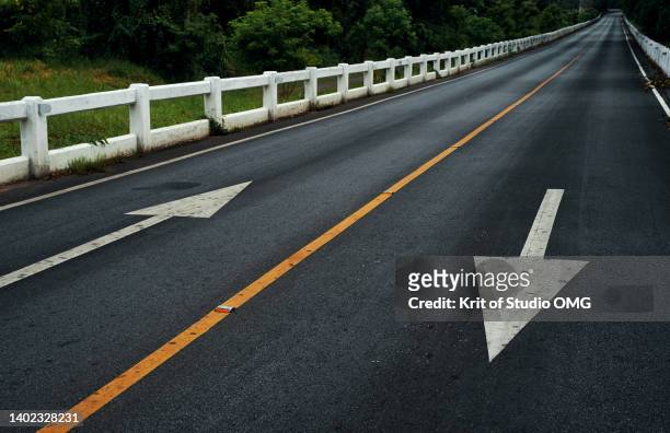 the asphalt road along the forest in the countryside - arrows landscapes stock pictures, royalty-free photos & images