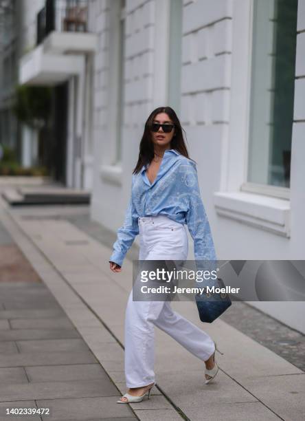 Milena Karl seen wearing a black Saint Laurent sunglasses, a light blue shirt blouse from Hermes, a white denim jeans from Monki, creme high heels...