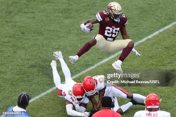 Stevie Scott III of the Michigan Panthers leaps over Mike Bell and De'Vante Bausby of the New Jersey Generals in the second quarter of the game at...