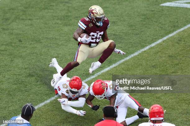 Stevie Scott III of the Michigan Panthers leaps over Mike Bell and De'Vante Bausby of the New Jersey Generals in the second quarter of the game at...