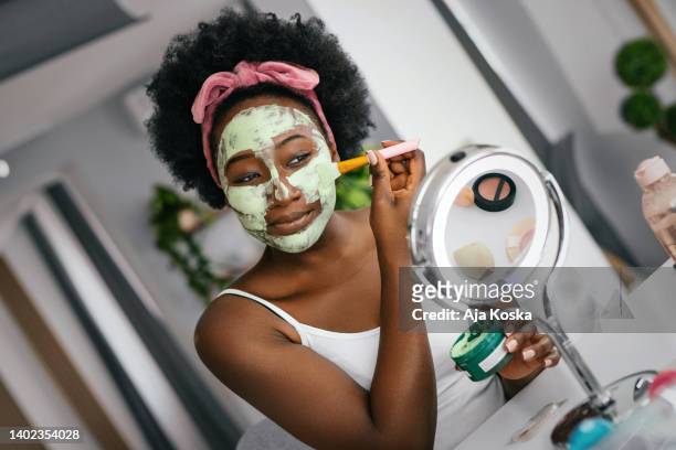 beautiful young woman applying facial mask. - tea tree stock pictures, royalty-free photos & images