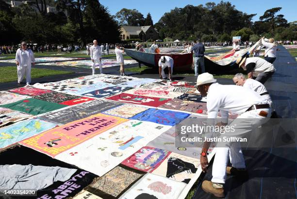 Volunteers unfold panels of the AIDS Memorial Quilt that are displayed on the lawn at Robin Williams Meadow in Golden Gate Park on June 11, 2022 in...