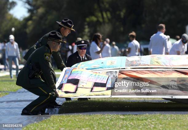 San Francisco sheriff deputies and firefighters unfold a panel of the AIDS Memorial Quilt that is being displayed on the lawn at Robin Williams...