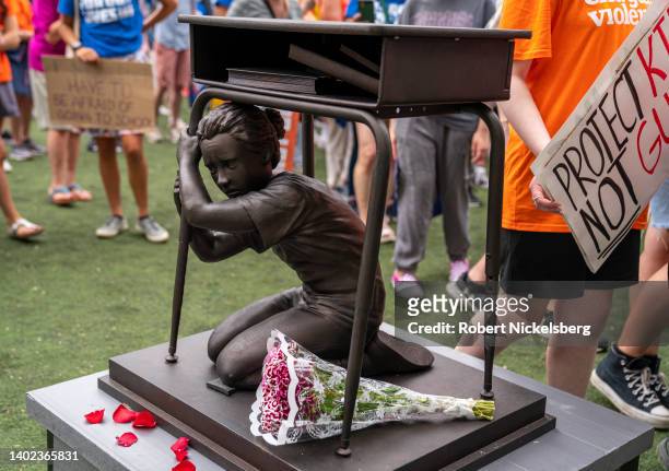 Participants walk by a metal desk with a school-age child hiding below it during a gun control protest March For Our Lives June 11, 2022 in the...
